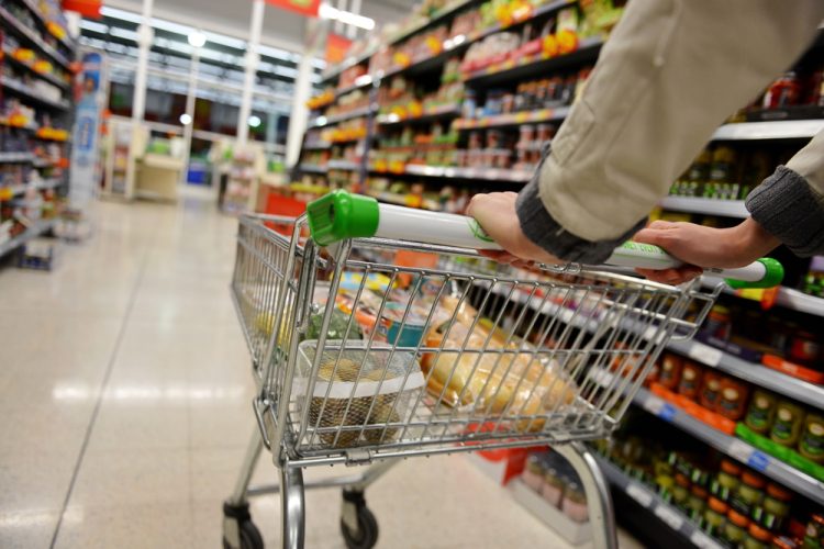 A Shopper Pushes a Trolley along a Supermarket Aisle - Image has a Shallow Depth of Field