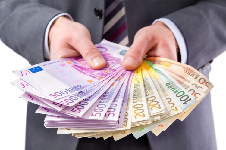 Businessman holding many euros banknotes